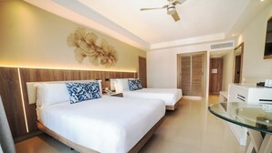 A hotel room with two beds, a glass table, a ceiling fan, and a decorative wall piece.