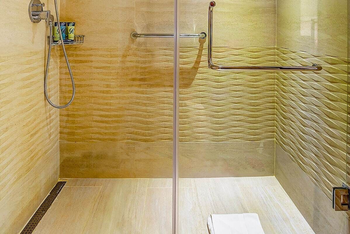 A shower with a glass door, a towel rack, and a shelf with toiletries.