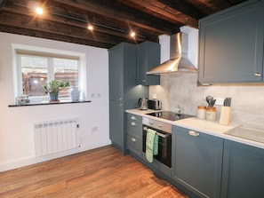 A modern kitchen with dark blue cabinets, a stainless steel range hood, a built-in oven, and a window with a plant on the windowsill. - THE LOFT, family friendly, with a garden in Glenmore, County Kilkenny (Kilkenny)