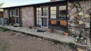 A stone building with a porch, potted plants, and a number '5' on the door. - Desert Serenity Private Patio Mountain View 1BR (Tucson)