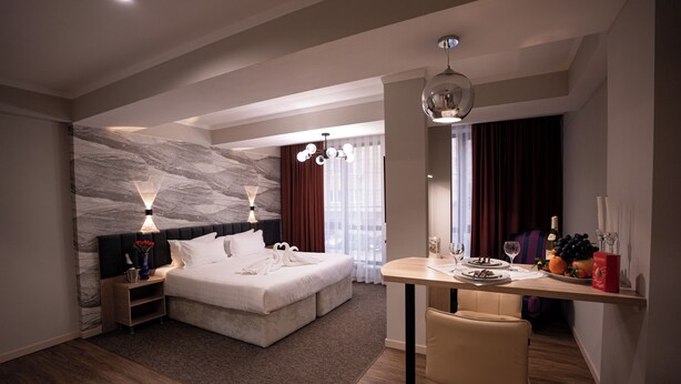 A modern hotel room with a large bed, a dining table, and a seating area. - Hotel Orto Asia (Bishkek)