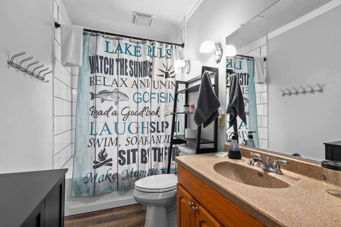 A bathroom with a shower curtain featuring motivational phrases, a sink with a mirror, and a toilet.