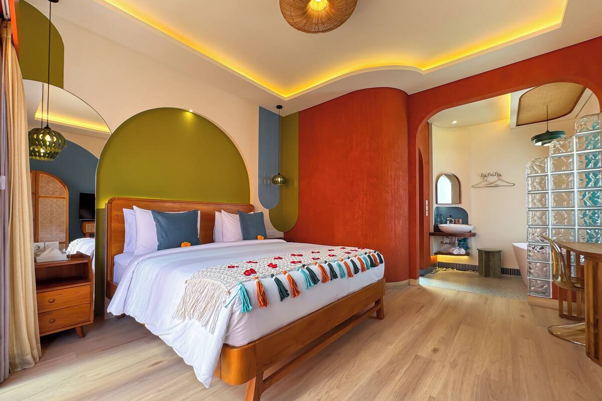 Ein modernes Hotelzimmer mit einem hölzernen Bett, einem Schminktisch mit Spiegel und einer kleinen Sitzecke.