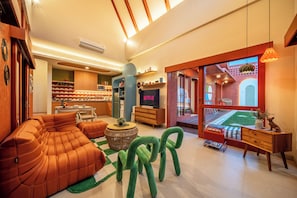 A modern living room with a sectional sofa, a television, and a dining area. - Kana Casa Canggu by Nagisa Bali (Canggu)