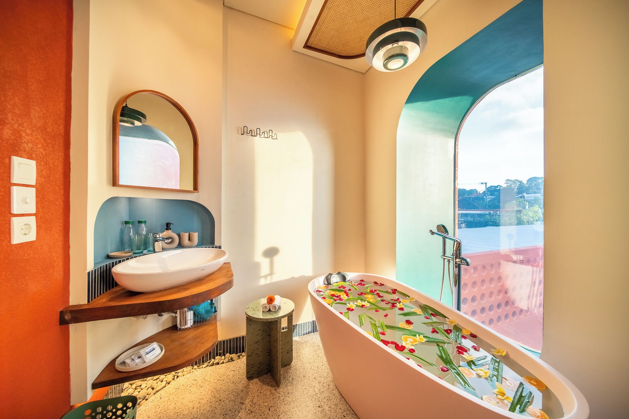 A modern bathroom with a freestanding bathtub, a large mirror, and a view of the city through a large window.