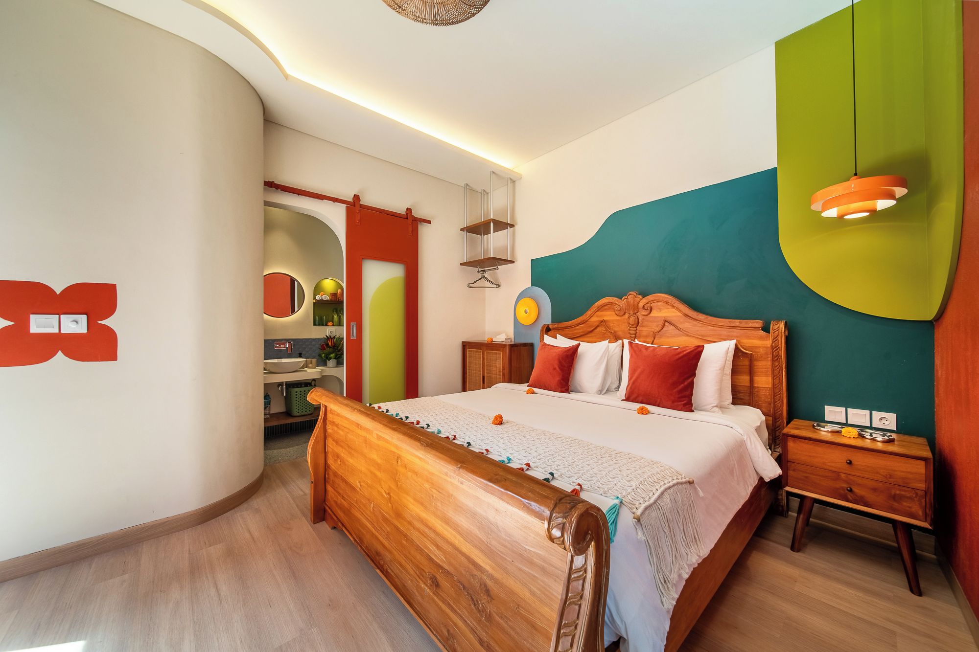 A modern bedroom with a wooden bed, a nightstand, a bedside table, and a bathroom visible through an archway.