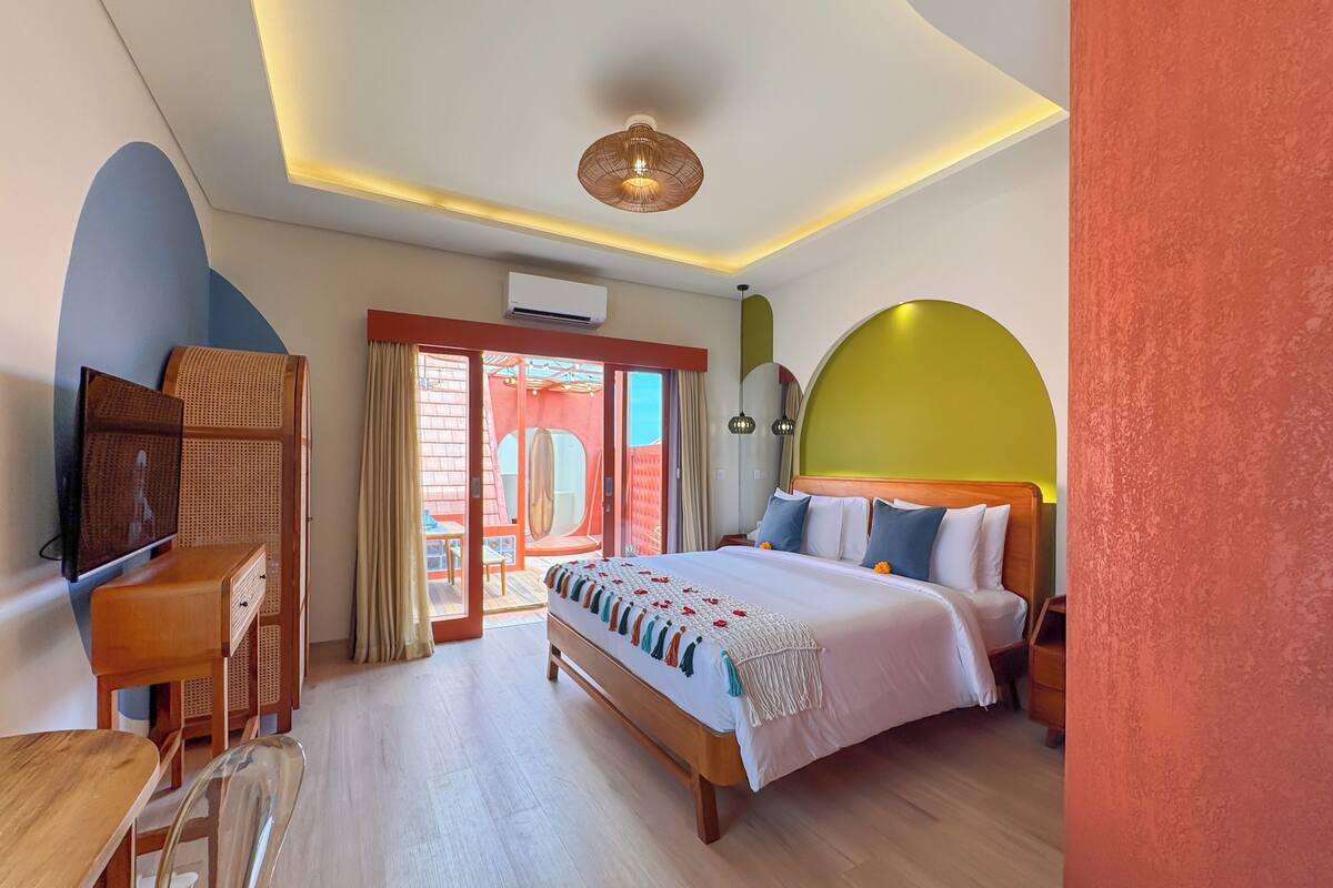 Ein Hotelzimmer mit Bett, Schreibtisch, Stuhl und Blick ins Freie.
