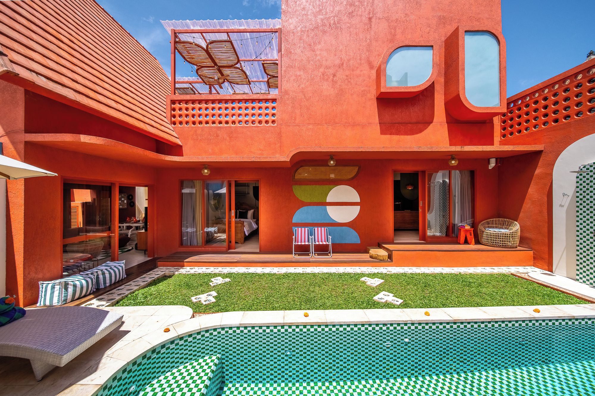 A modern building with a swimming pool, outdoor seating, and a clear sky.
