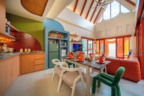 A modern kitchen with a dining area, a sofa, and a view of the outside. - Kana Casa Canggu by Nagisa Bali (Canggu)