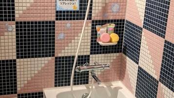 Bañera con ducha, toallas, jabón, shampoo