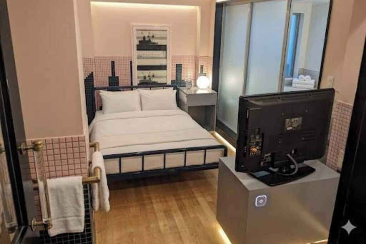 Une chambre d’hôtel avec un lit, une table de chevet, une télévision et une fenêtre.