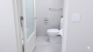 A small, modern bathroom with a toilet, a towel rack, and a shower area. - HOTEL CANDY BOX (Osaka)