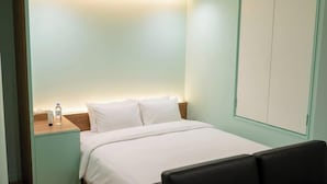 A hotel room with a bed, a nightstand with a bottle, and a wardrobe. - HOTEL CANDY BOX (Osaka)