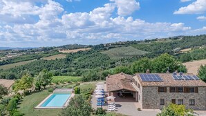 Eine Villa mit Swimmingpool, Außenbereich mit Sitzgelegenheiten und Solaranlage.