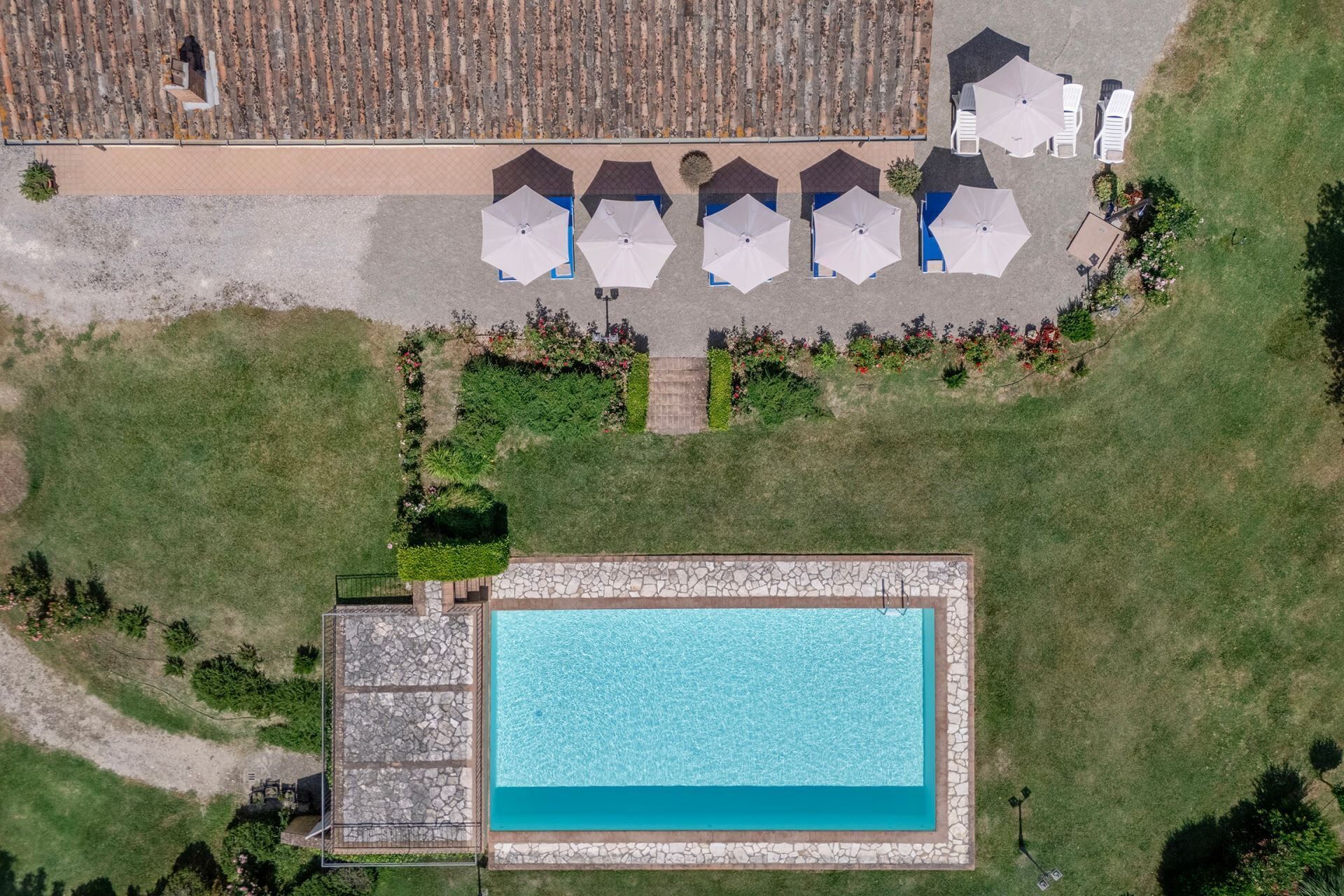 An aerial view of a resort with a swimming pool, lounge chairs, and umbrellas.
