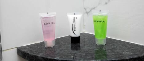 Three toiletry bottles on a marble countertop.