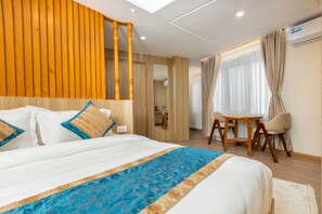 Ein Hotelzimmer mit einem großen Bett, Holzwandverkleidung, einem kleinen Tisch mit Stühlen und einem Fenster mit Vorhängen.