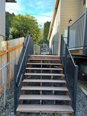 A set of wooden steps leading up to a house with a metal railing on both sides.