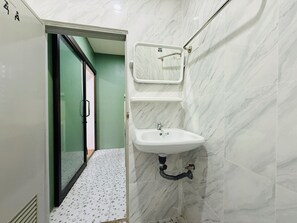 A bathroom with a white sink, a mirror, and a shower area.