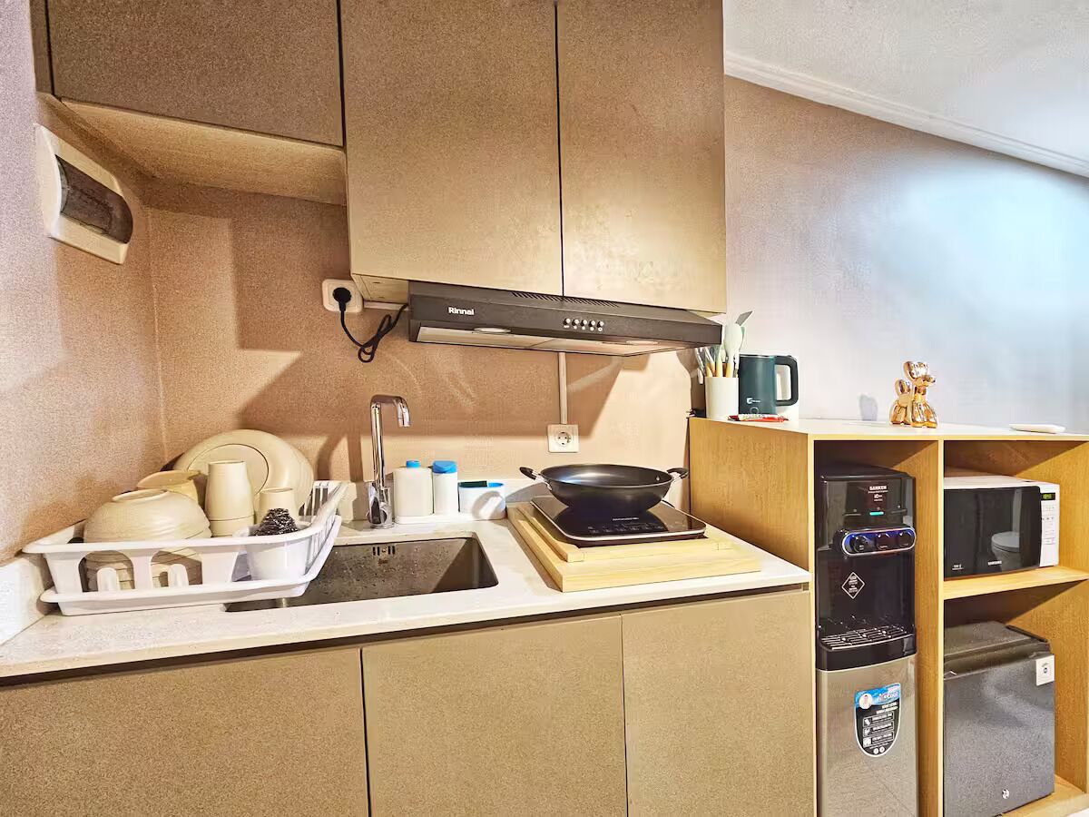 A compact kitchen with a sink, stove, microwave, and a water dispenser.