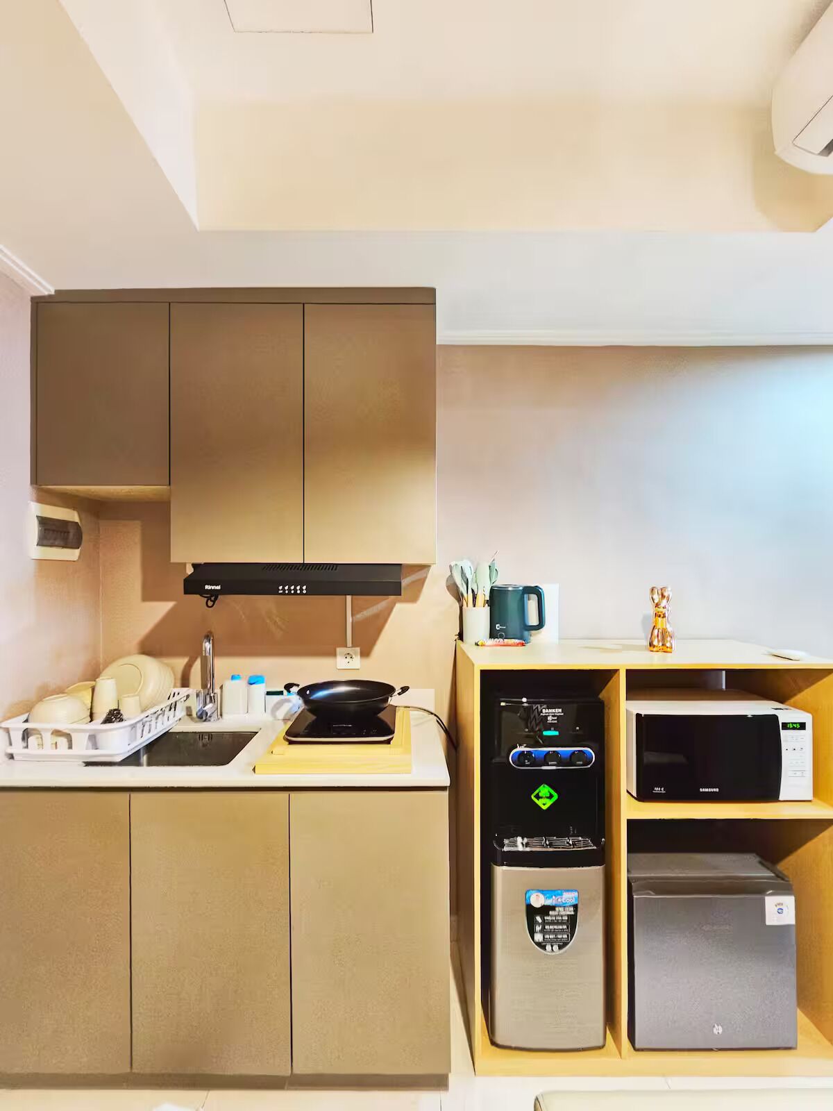 A compact kitchen with a stove, microwave, and refrigerator, along with a sink and cabinets.