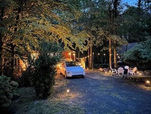 A vehicle parked in a forested area with a pathway leading to a building.