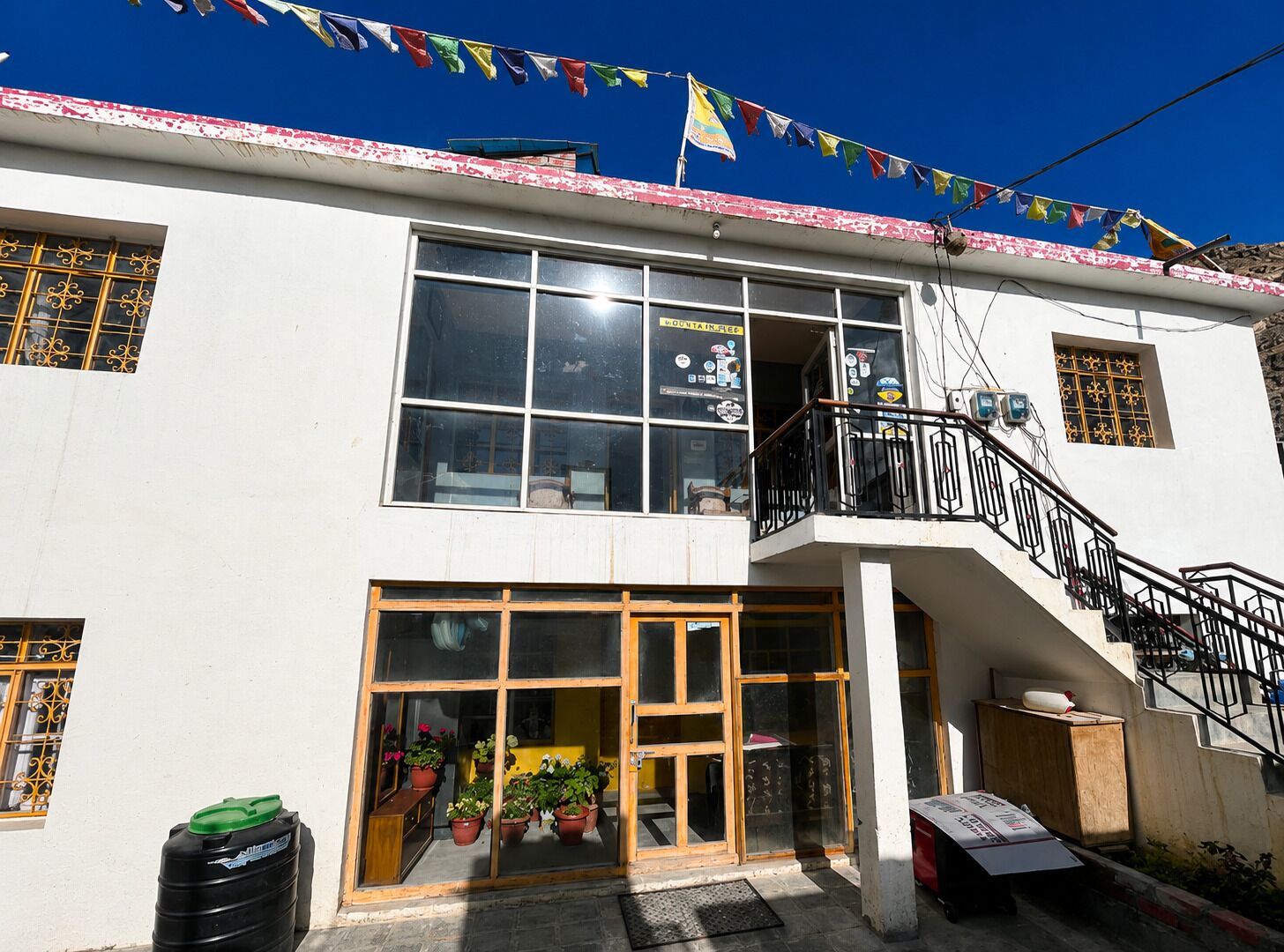 A building with a balcony, a staircase, and a storefront with potted plants.