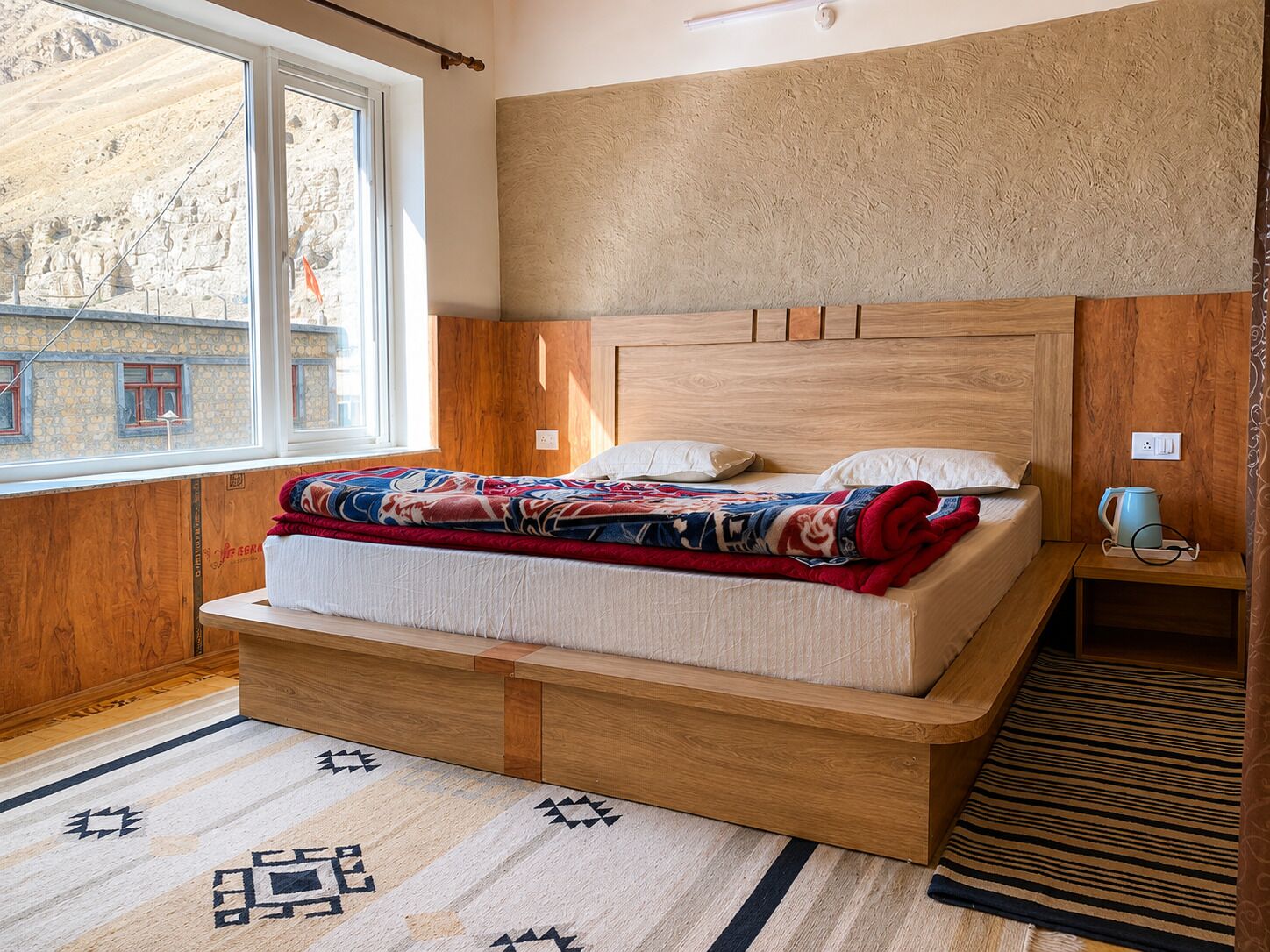 A bedroom with a wooden bed, a window, and a view of a building outside.