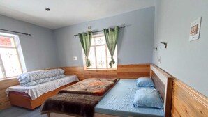A bedroom with two beds, a window with curtains, and a zebra-patterned rug. - Juniper Home Kaza By Mountain Bee (Spiti)