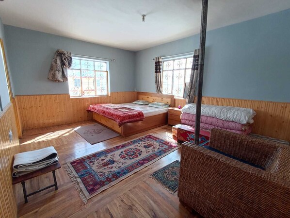 A room with a bed, a nightstand, a wicker chair, and a window with curtains. - Juniper Home Kaza By Mountain Bee (Spiti)