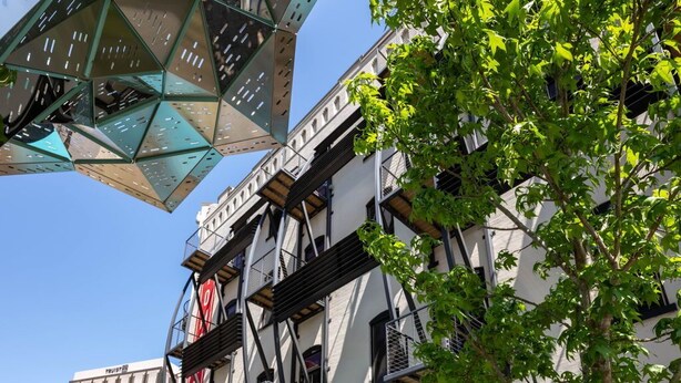 Un espace extérieur aménagé avec des tables et des chaises, une colonne aux couleurs vives et un bâtiment doté d’échelles de secours.