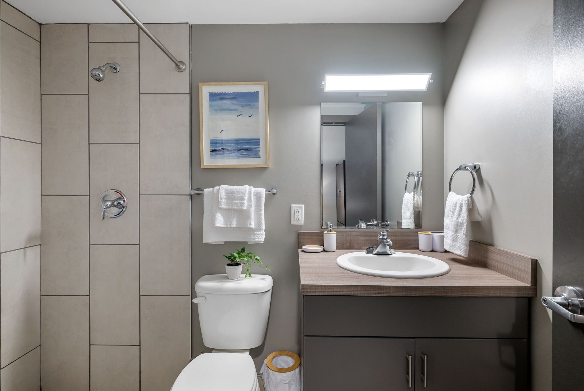 Un baño moderno con ducha, inodoro, lavamanos y espejo.