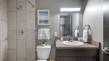 Un baño moderno con ducha, inodoro, lavamanos y espejo.