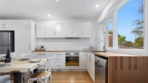 Eine moderne Küche mit weißen Schränken, einem Edelstahlkühlschrank und einem Holztisch.