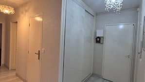 Ein Flur mit weißen Türen, einer Uhr an der Wand und einer Deckenleuchte.