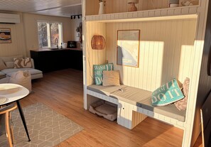 A cozy room with a bed, a dining table, and a kitchen area. - Lovely holiday home with garden near water (Rødby)