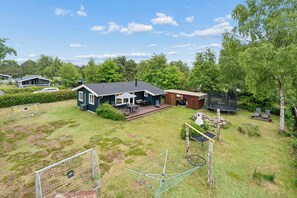 Ein Wohnhaus mit Garten, Trampolin, umzäunter Spielbereich und Terrasse mit Gartenmöbeln.