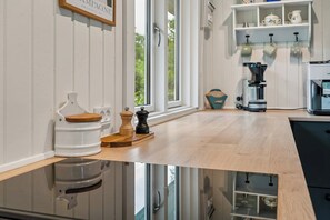 A modern kitchen with a wooden countertop, a coffee machine, and a window with a view of greenery. - Lovely holiday home with garden near water (Rødby)