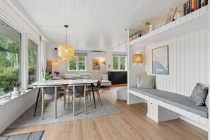 Ein modernes Interieur mit Essbereich, Sitzgelegenheiten und Blick auf Grünflächen.