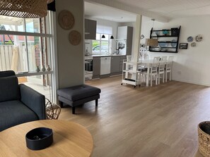Un salon moderne comprenant un canapé, une table basse ronde et un coin repas avec des chaises et une table.