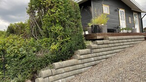 Une maison avec un toit en pente, une terrasse en bois et une allée gravillonnée.
