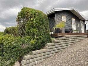 Ein Haus mit geneigtem Dach, einer Holzterrasse und einer Schotterauffahrt.