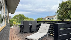 Une terrasse en bois avec une chaise longue, une table et des chaises.