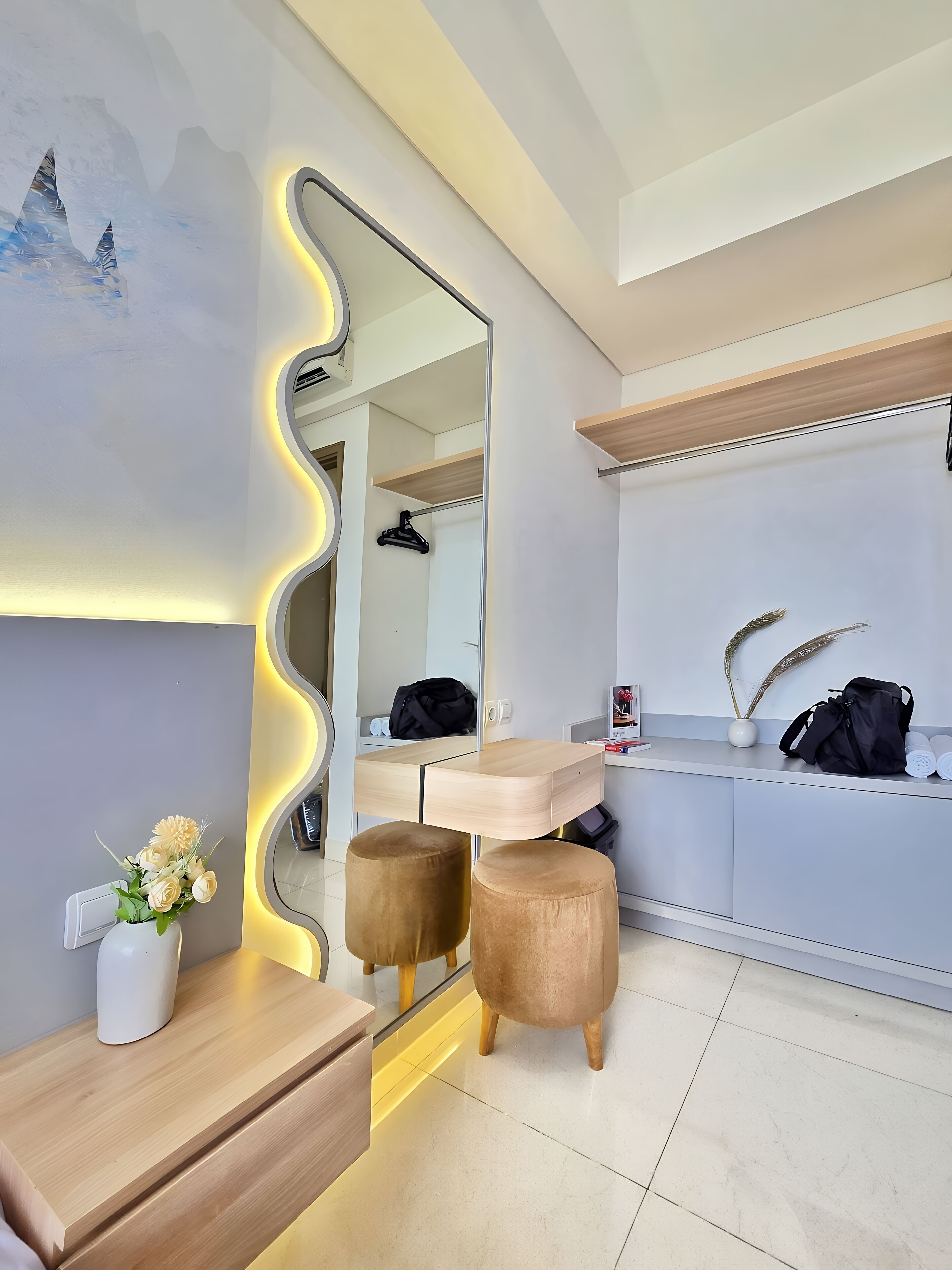 Een moderne badkamer met een wastafelmeubel, een grote spiegel en een houten meubel met een bloevas.