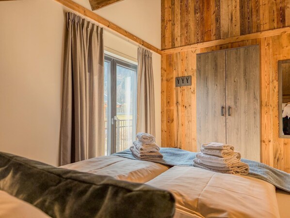 Un dormitorio con un armario de madera, una cama con toallas y una ventana con cortinas.