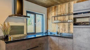 Uma cozinha moderna com uma janela grande, painéis de parede de madeira e eletrodomésticos embutidos.