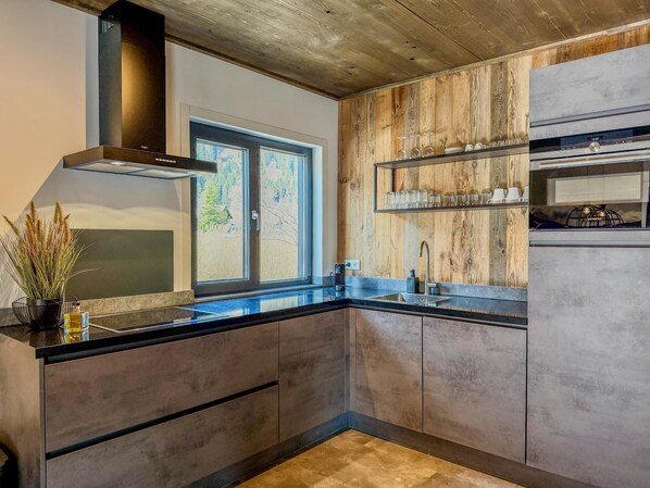 Una cocina moderna con un ventanal grande, paneles de madera y electrodomésticos integrados.