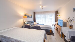 Quarto de hotel com cama, sofá, escrivaninha e televisão.