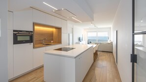 Eine moderne Küche mit Kochinsel, integriertem Backofen und Meerblick.