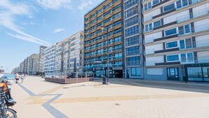 Ein mehrstöckiges Hotel mit modernem architektonischen Design, mit Balkonen, großen Fenstern und einem gepflasterten Weg.